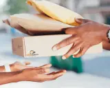 Ręce przekazują sobie paczki i koperty – idealne, by w co zapakować paczkę na Vinted.