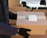 Kurier w czarnej rękawiczce trzyma paczkę z etykietą DPD. To pokazuje, ile jest ważna etykieta DPD dla sprawnej dostawy.