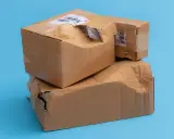 Produkt uszkodzony, ale paczka jest cała. Dwie kartonowe paczki, jedna na drugiej, z widocznymi uszkodzeniami i dziurami.