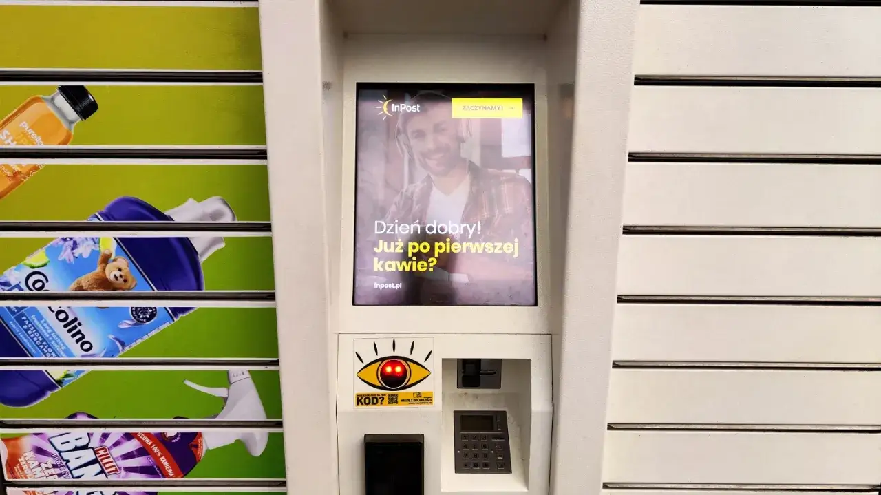 Automat InPost z ekranem wyświetlającym uśmiechniętego mężczyznę i pytaniem